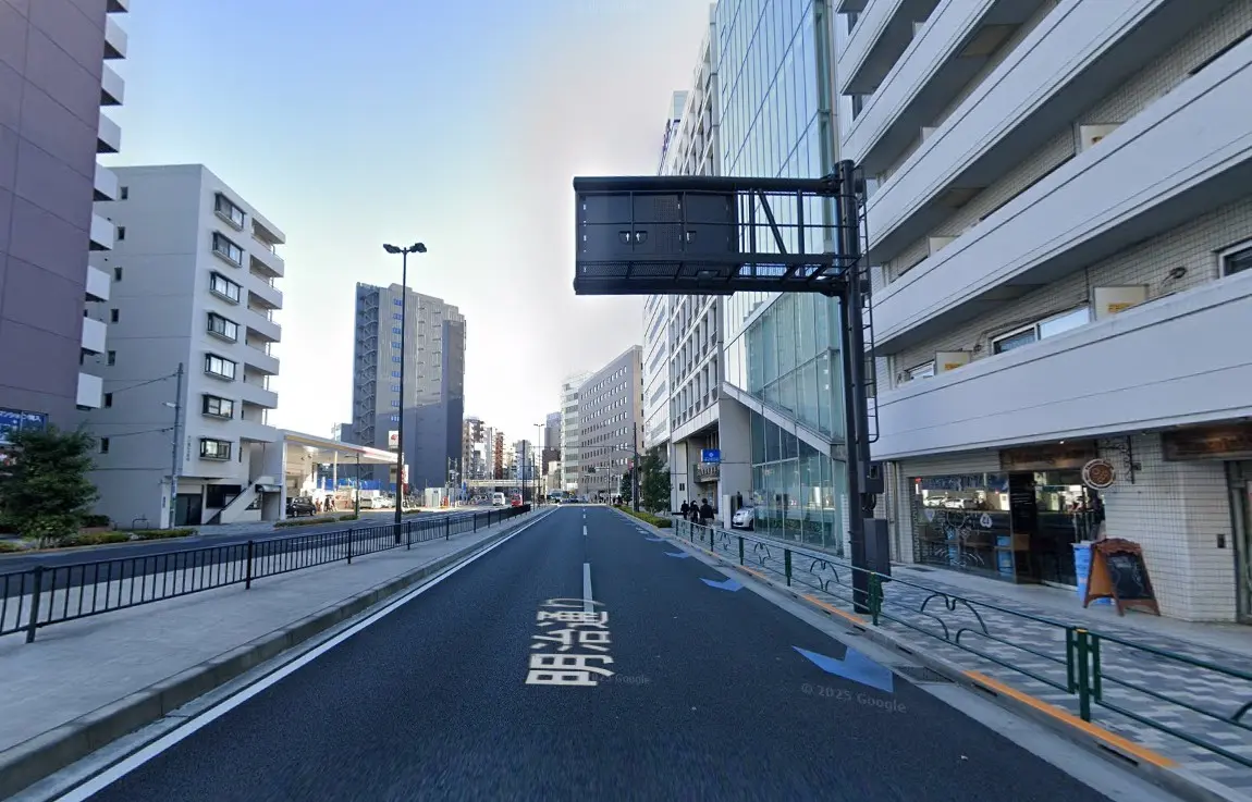 - 都市部の道路沿いに立ち並ぶ高層ビル、側に歩道と透明なガラスの建物が特徴的な風景