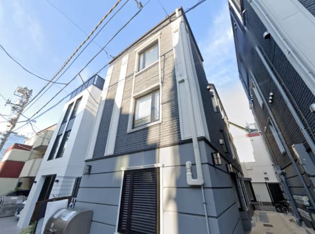 - モダンなデザインの外観を持つ建物、横長の窓とシャープなラインが特徴的で、周囲には電線が走る都会的な景観