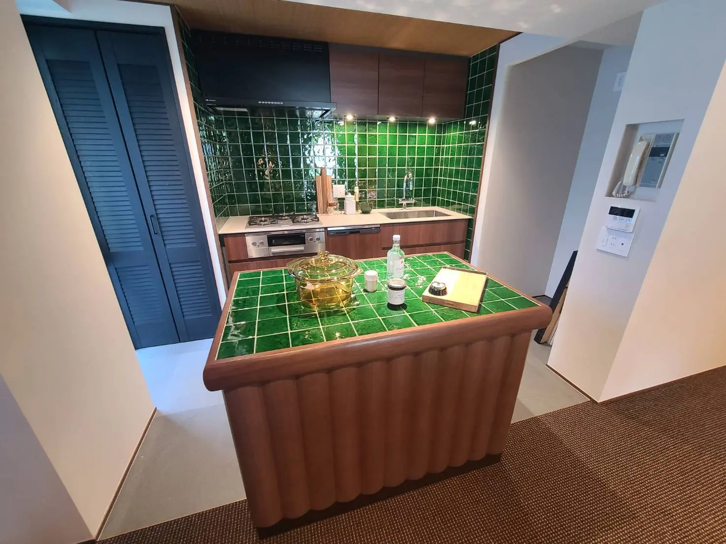 - 緑のタイルと木製のカウンタートップが特徴のモダンなキッチン、シンプルなデザインでスタイリッシュなインテリア