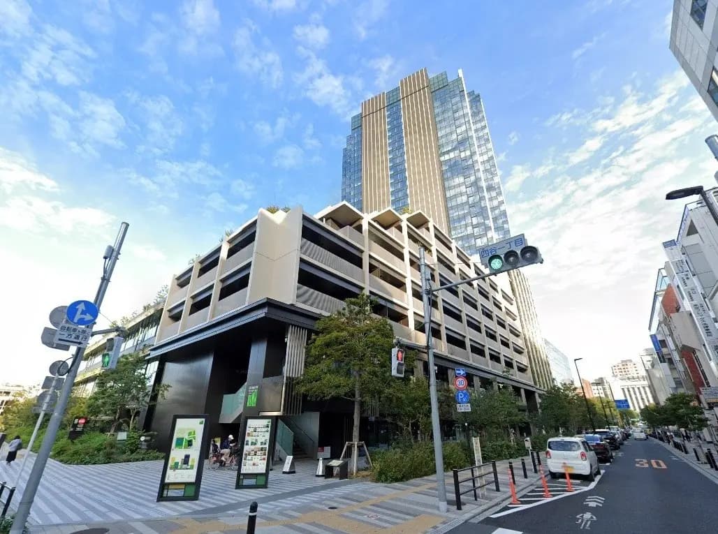 - 近未来的なデザインの駐車場と高層ビルの様子、緑豊かな landscaping と交通信号が見える都市の景観