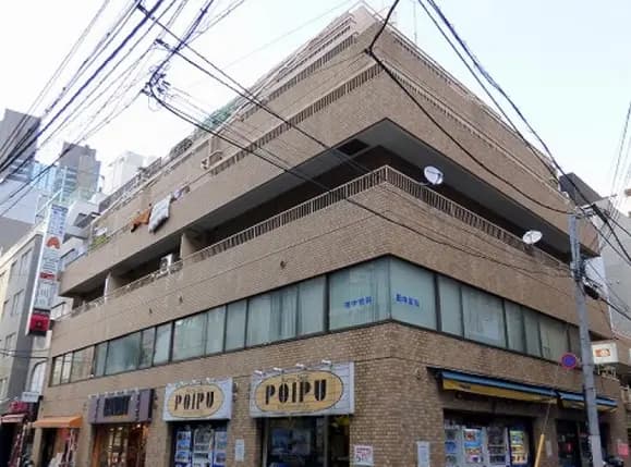 - 鉄筋コンクリート造の商業ビル、ブリックタイルの外壁、1階には店舗があり周囲に電線が見える景観