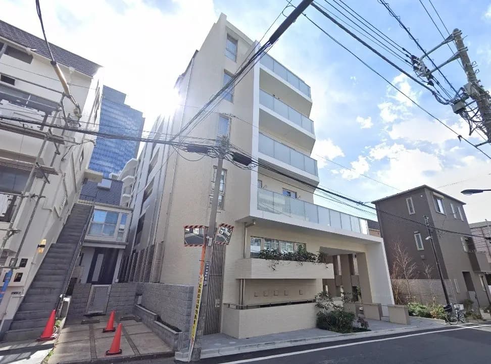 - 近代的なデザインの五階建てのアパート、透明なバルコニーとガラスの手すりが特徴、周囲には住宅街が広がる街並み
