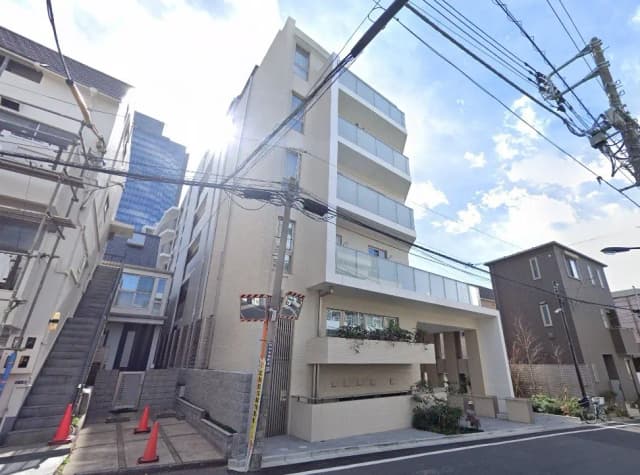 - 近代的なデザインの五階建てのアパート、透明なバルコニーとガラスの手すりが特徴、周囲には住宅街が広がる街並み