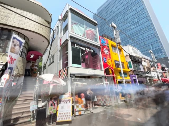 - 明るい商店街の風景、カラフルなファサードの店舗、賑わいのある通りと階段のあるビルの外観