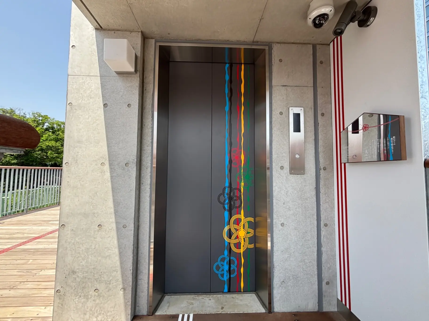 - カラフルなデザインのエレベーターの扉、現代的なコンクリートの壁と金属のパネルが特徴的な建物のエントランスの風景
