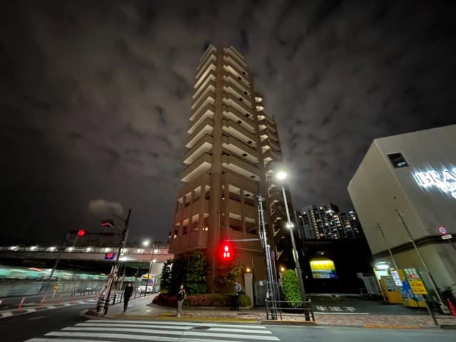 夜の都市の風景、高層マンションと信号機、雲が広がる空、歩行者がいる交差点の様子