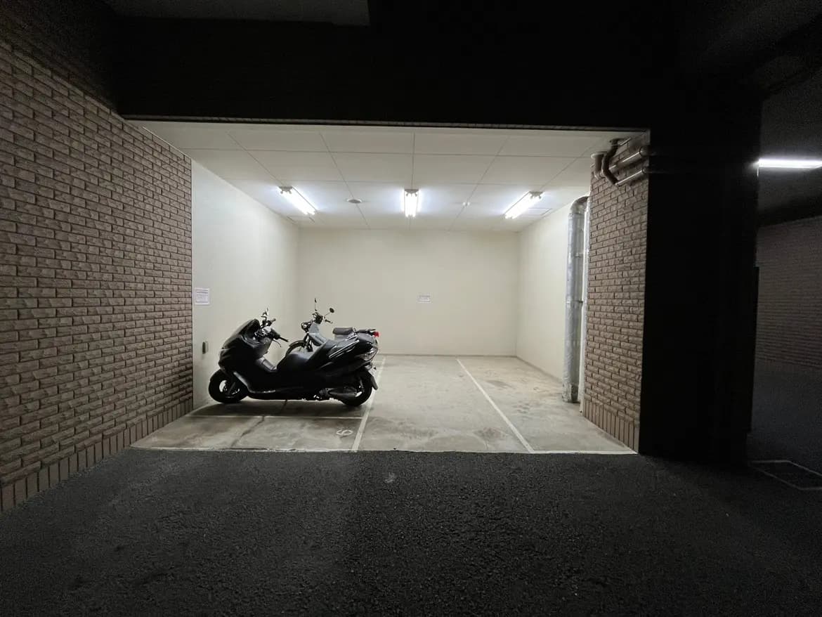 - 郵便受けの横に駐車された二台の黒いスクーター、明るい照明の屋内駐車場の内部画像