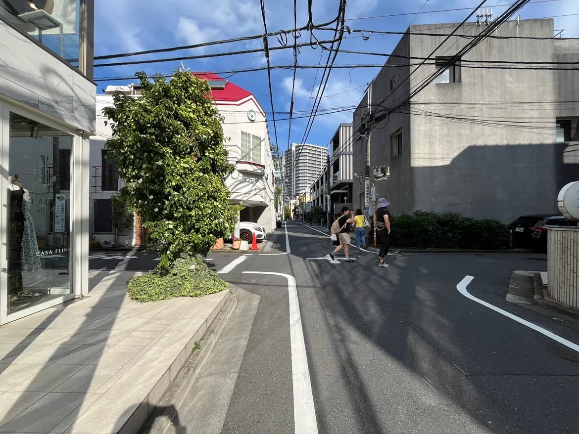- 街角の風景、緑豊かな木とモダンな建物が並ぶ通り、歩行者が交差点を渡る様子