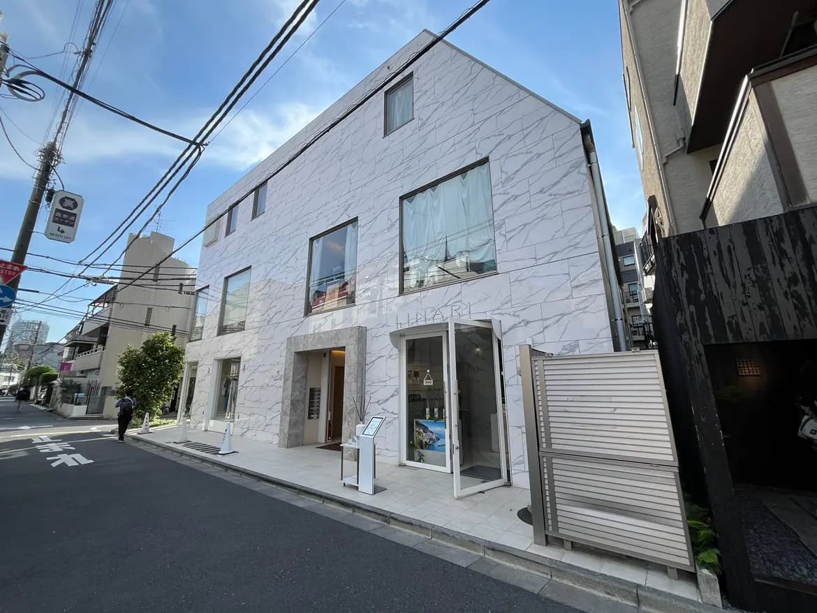 - 大理石の外壁を持つモダンな建物、広めの窓からは明るい光が差し込むデザイン、交通路に面した街並みの一部