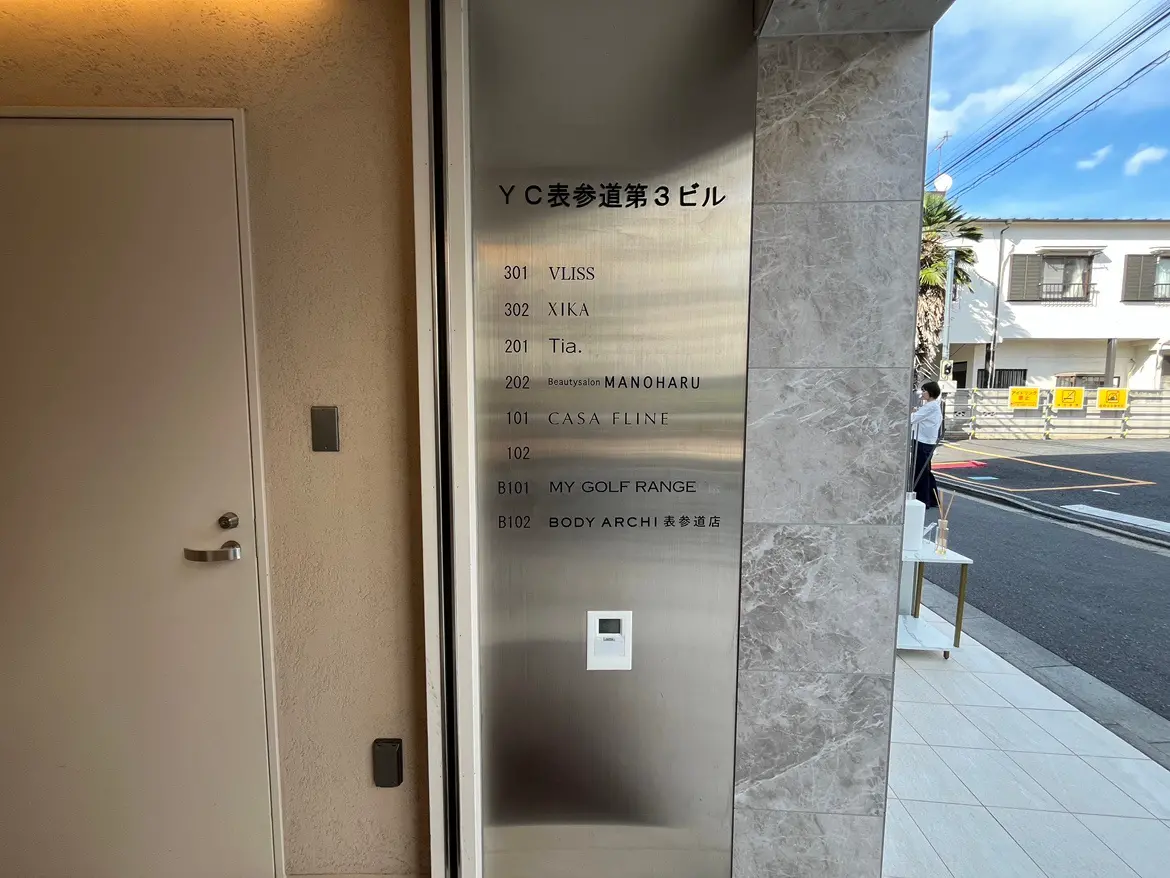 - YC表参道第3ビルのエントランスと室番号表示、複数の店舗名が記載されたスタイリッシュなサインボード