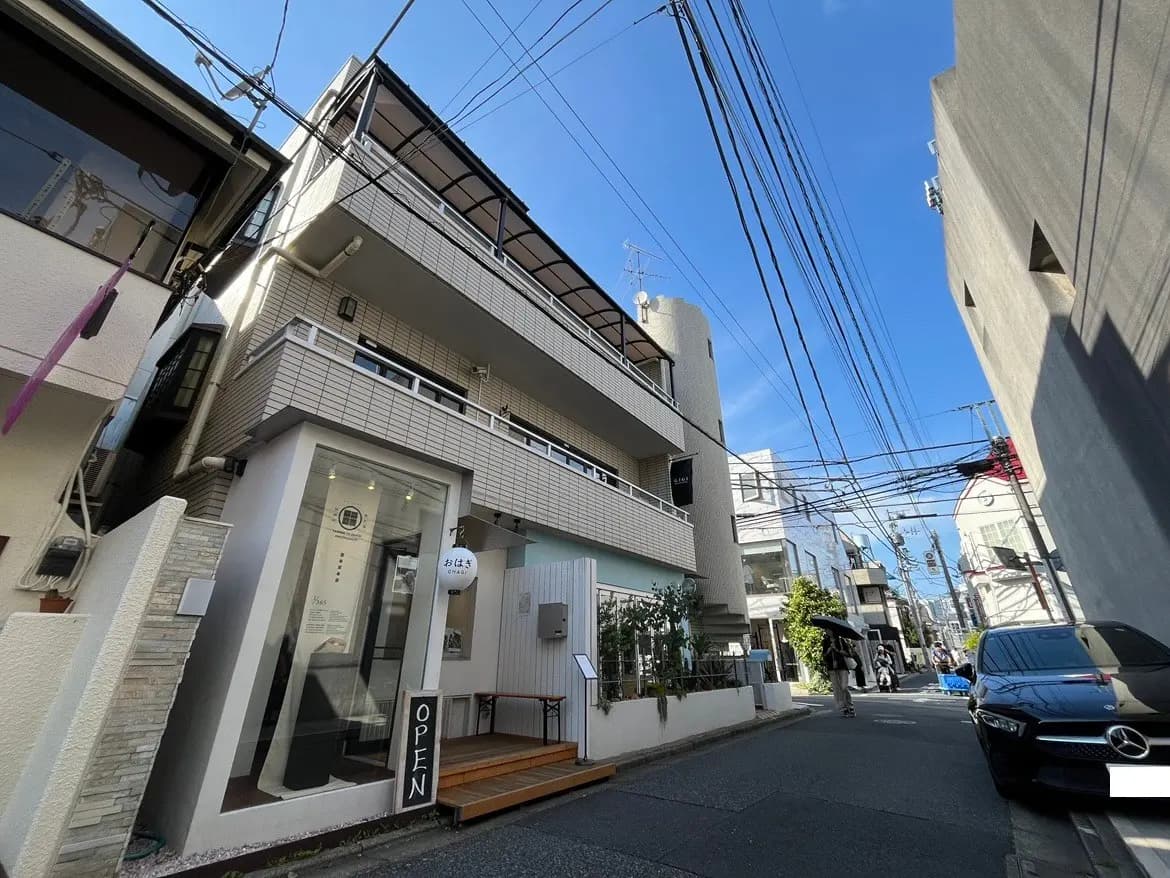 - 明るい青空の下、現代的な外観のコーヒーショップの入口、オープンの看板と周囲の建物が見える街角の風景