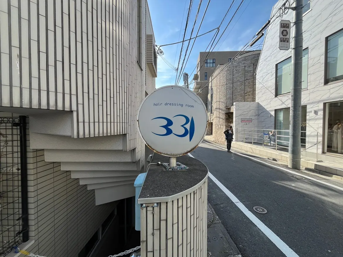 - 髪の美容室「331」の看板、モダンな建物と周辺の街並みを背景にした風景