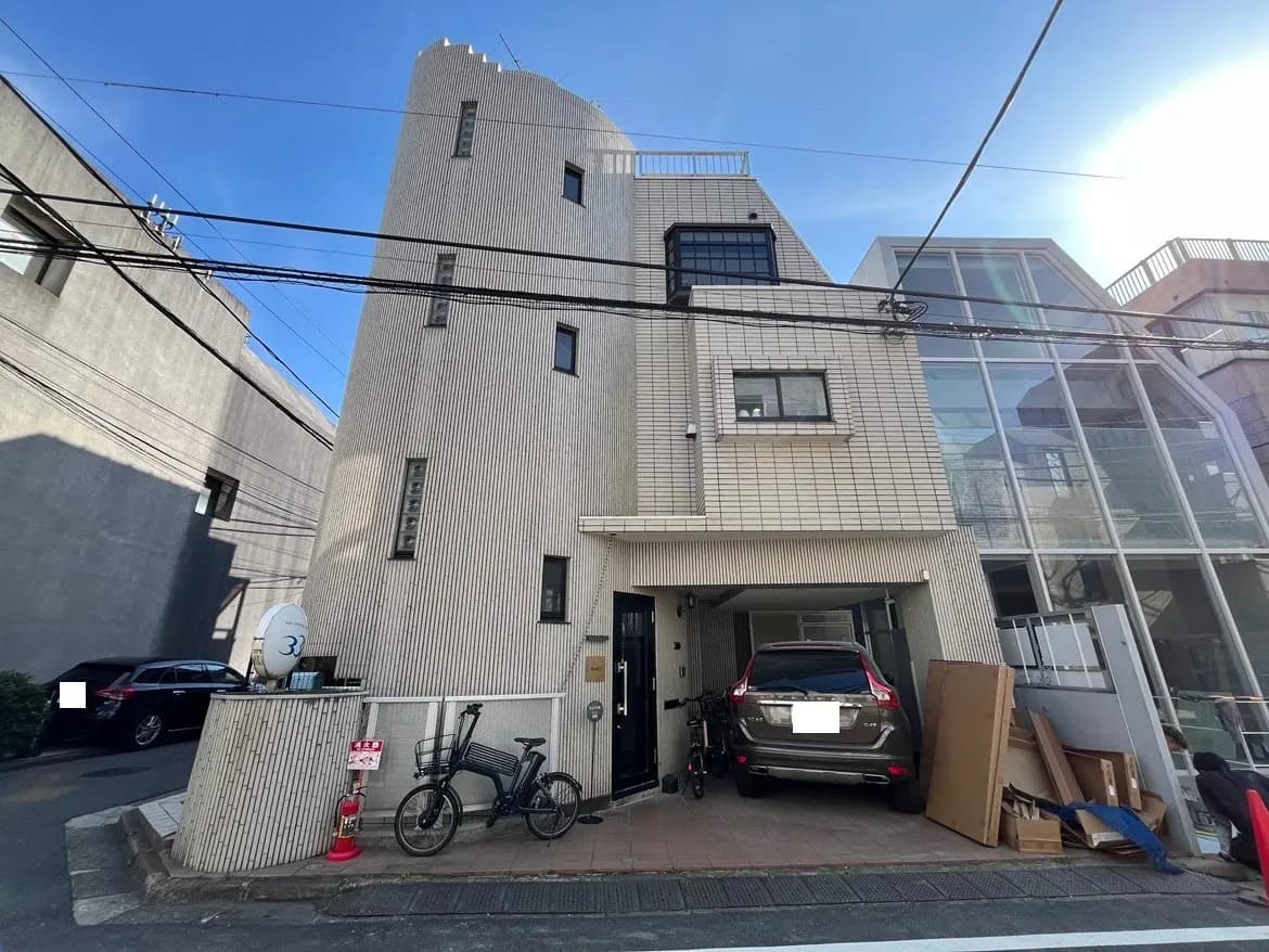 - モダンな外観の住宅、ストライプ状のタイルとガラス、大きな窓、駐車スペースに車と自転車がある街並みの風景