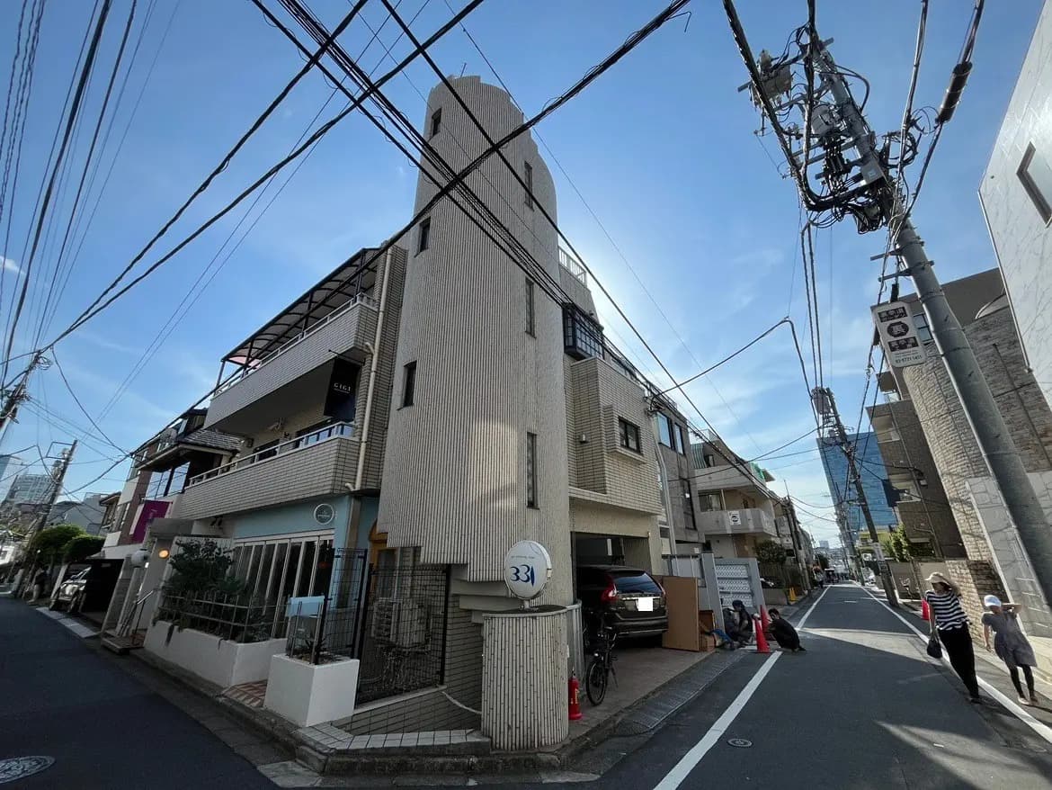 - 現代的な住宅街の外観、モダンなデザインの建物と電線が交錯する風景、青空の下での街並み