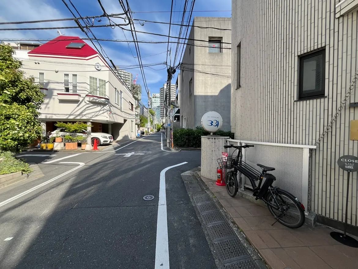 - 緑豊かな街並みの一角にある自転車とマンション、晴れた空に映える建物と電線のある風景
