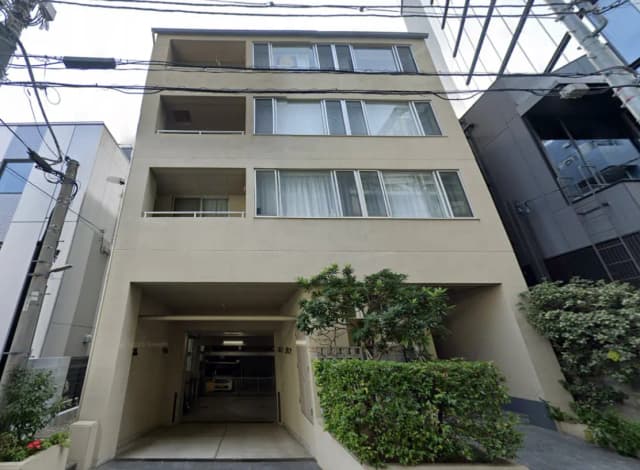 - シンプルでモダンな外観のマンション、バルコニーや大きな窓が特徴的、前庭には植栽がある景観