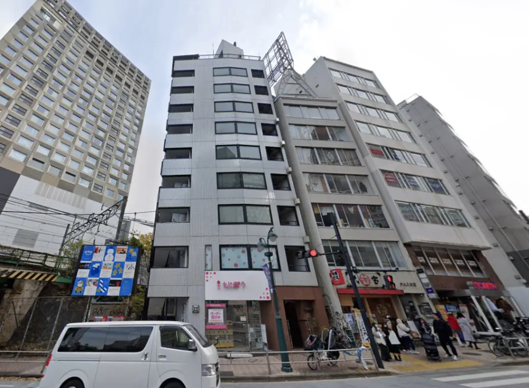 - 都市のビル群、様々なデザインの建物が並ぶ街並み、手前に交通信号と歩行者がいる風景