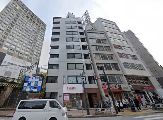 - 都市のビル群、様々なデザインの建物が並ぶ街並み、手前に交通信号と歩行者がいる風景
