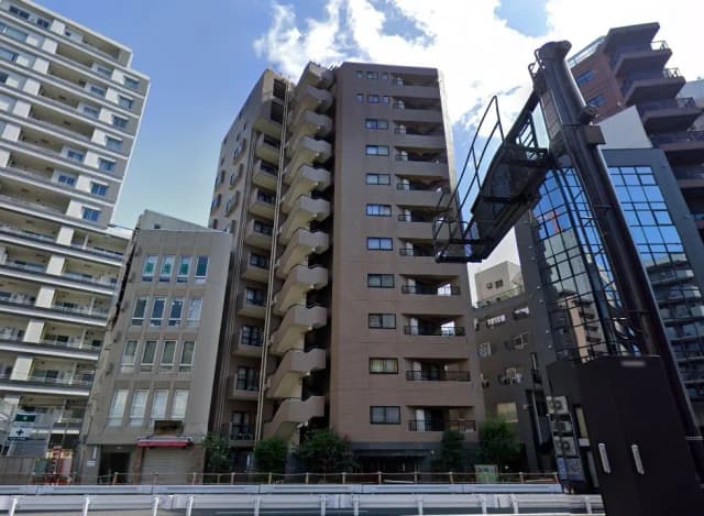 - 都市の中に佇む高層マンションの外観、近隣のビルと共存する景観、バルコニーがある建物