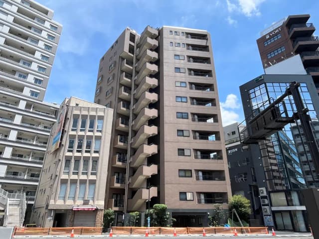 - 都市部のビル群、異なるデザインのマンションと商業ビル、晴れた青空の下に立ち並ぶ風景