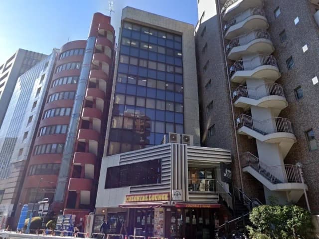 - 現代的なデザインのビルが立ち並ぶ都市風景、カラフルな外観の飲食店「コロニアルラウンジ」が目立つ場所