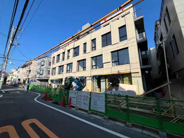 - 鉄筋コンクリート造の現代的な建物の外観と工事中の景観、青空の下での道路沿いの様子