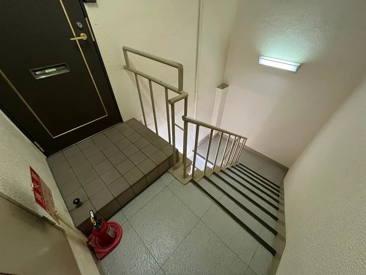 - 階段の下から見上げたアングル、黒いドアと手すり、明るい照明がある室内の風景