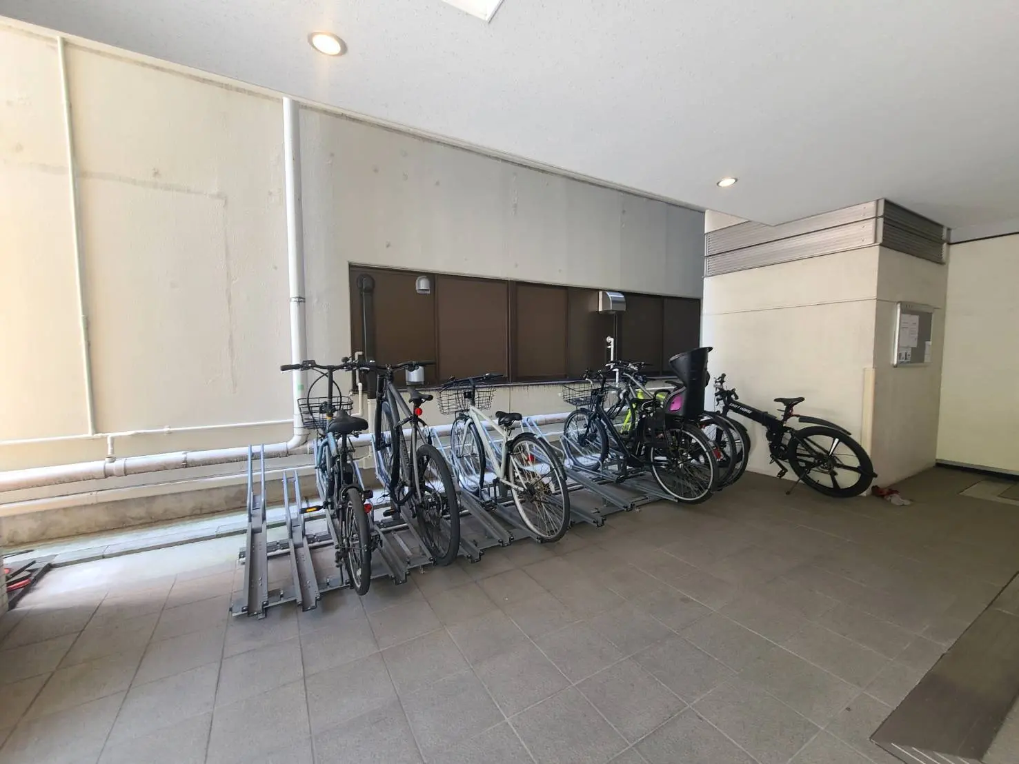 - 駐輪場に並ぶ自転車、金属製のラックに収納されている、明るい照明の室内風景