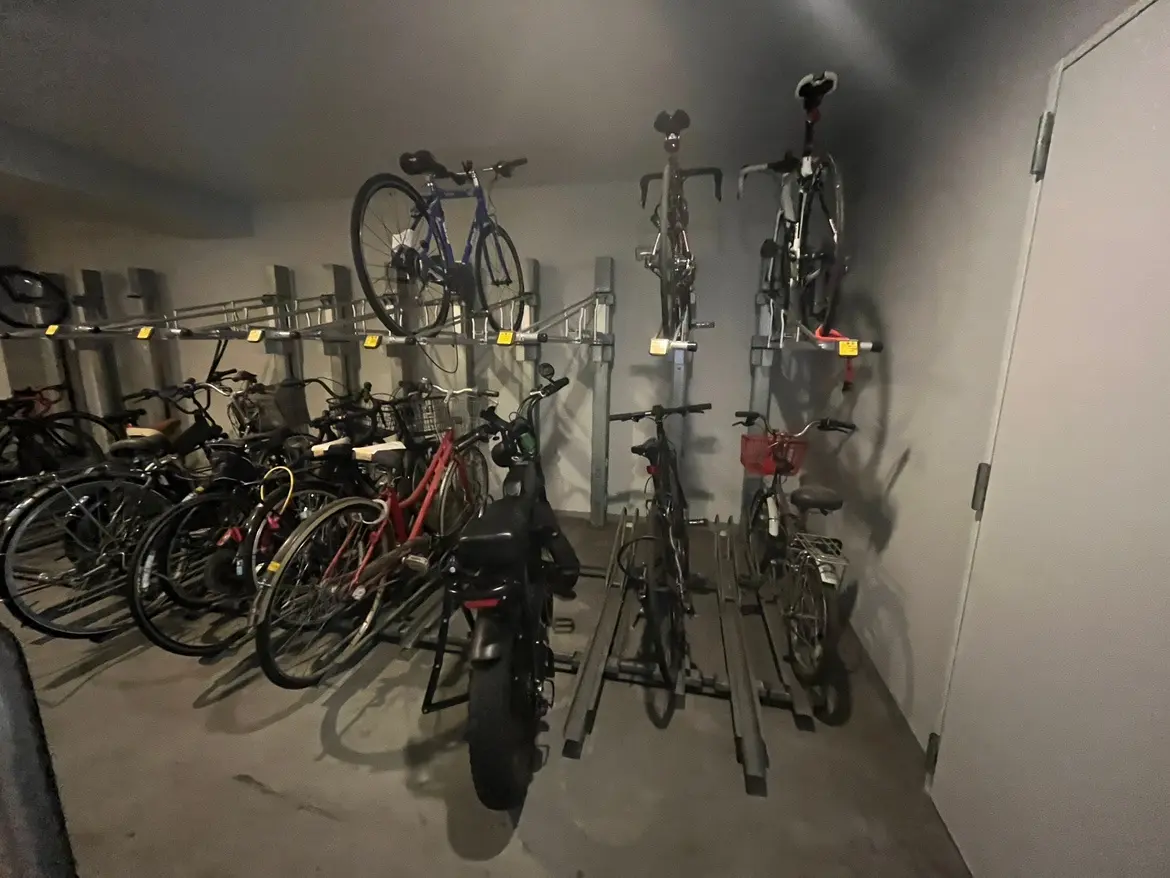 - 自転車が整然と配置された地下駐輪場、壁に掛けられた自転車と地面に置かれた多数の自転車が見えるシーン