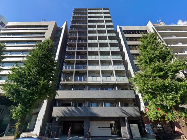 - 現代的なデザインの高層マンション、シャープな外観とバルコニーを持ち、都市の風景と緑の木々を背景にした写真
