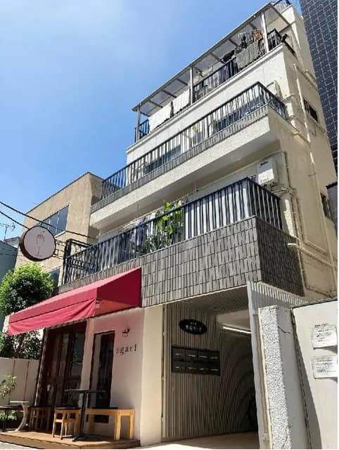 - 近代的な外観の建物、バルコニーと赤いテント、看板には「agart」と書かれたカフェのエントランス