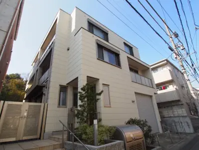 - モダンなデザインの三階建て住宅、白い外壁と大きな窓、周囲に緑豊かな植栽がある静かな街並み
