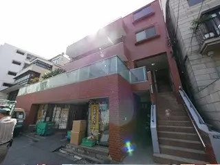 - 現代的なデザインの赤レンガの建物、ガラスの手すりのバルコニーが特徴で、周囲に工事現場が見える街の風景
