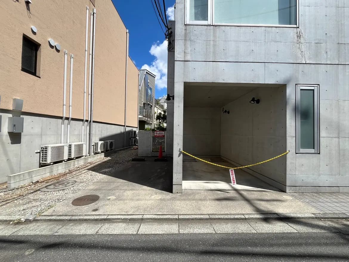 - コンクリート壁の建物と周囲の景観、舗装された道路、壁に取り付けられたエアコンの室外機が並ぶ光景