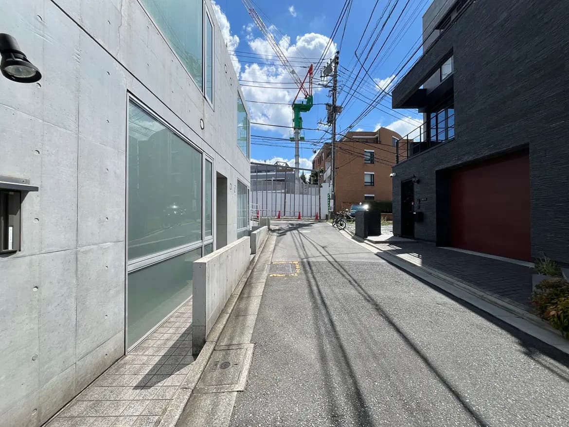- コンクリートとガラスのモダンな建物が並ぶ街並み、青空と白い雲が広がる背景の都市風景