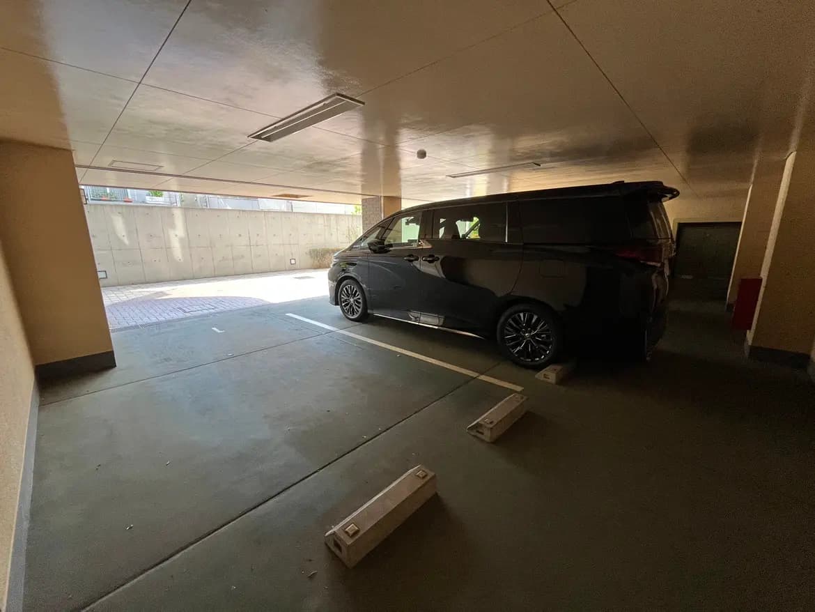 - 駐車場に停車した黒いミニバン、広々としたスペースと明るい自然光が差し込む様子