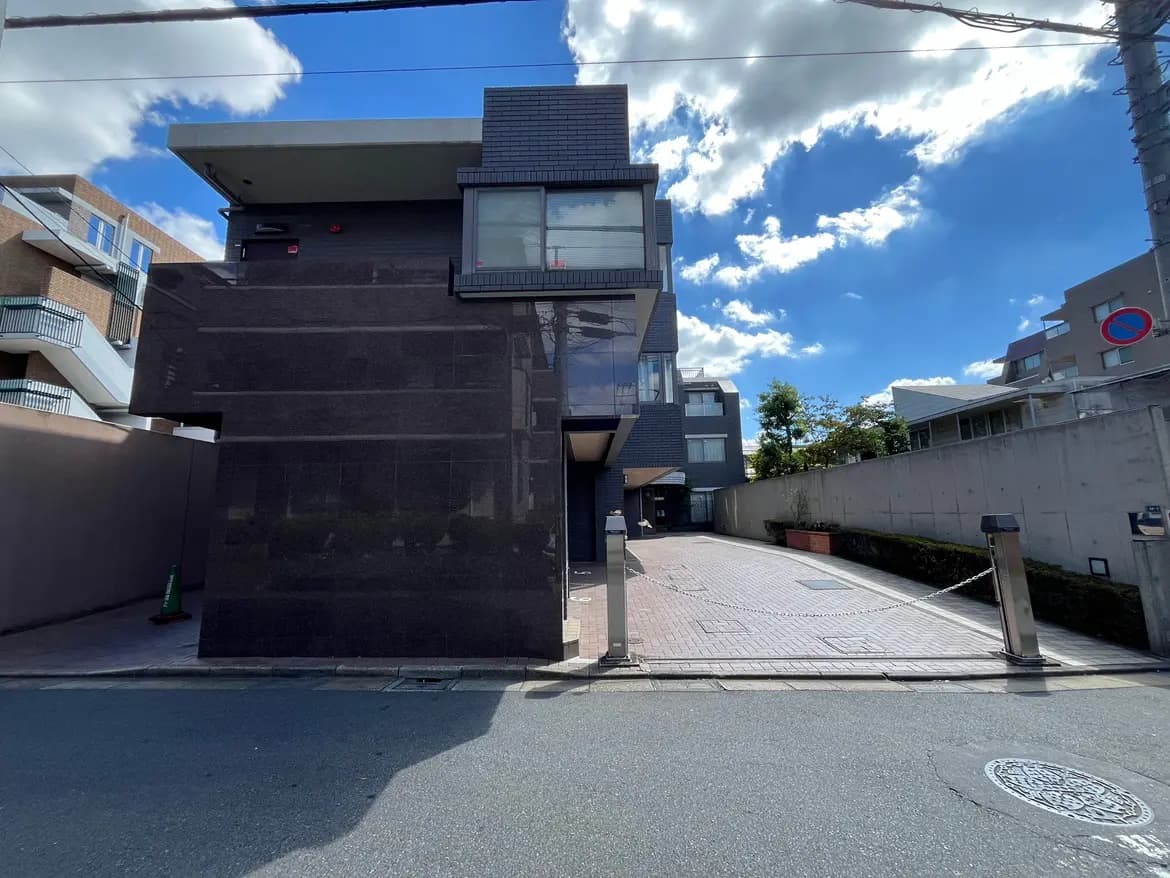 - モダンなデザインの建物外観、ガラスと黒いタイルの仕上げ、青空と白い雲が広がる風景