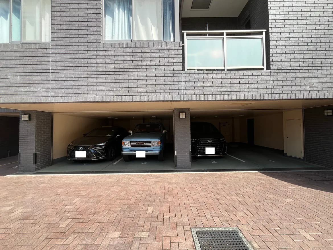 - モダンなアパートの地下駐車場に停車したレクサスとトヨタの車、背後にはスタイリッシュなブロック壁と明るい照明の空間