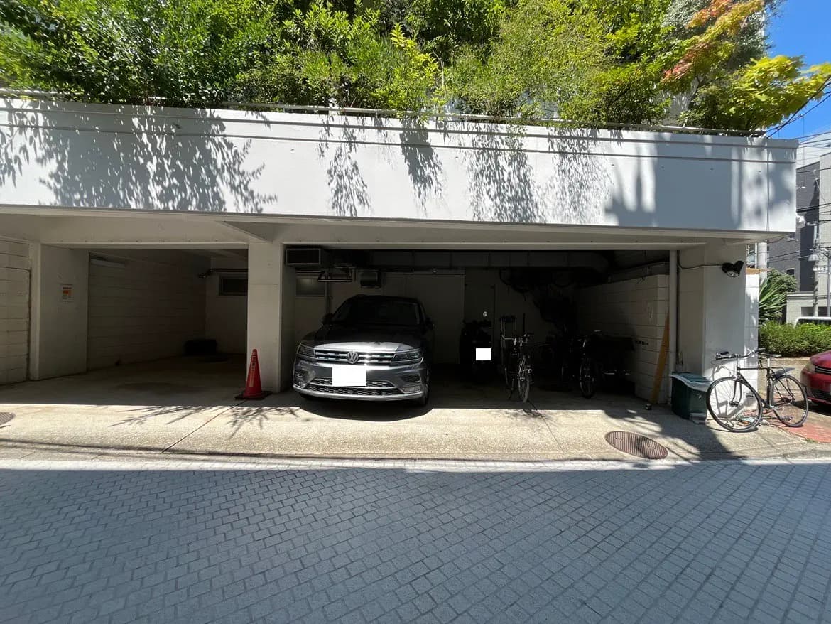- 駐車場に停まったフォルクスワーゲン車と、周囲に並ぶ自転車、緑の植物がある明るい景観