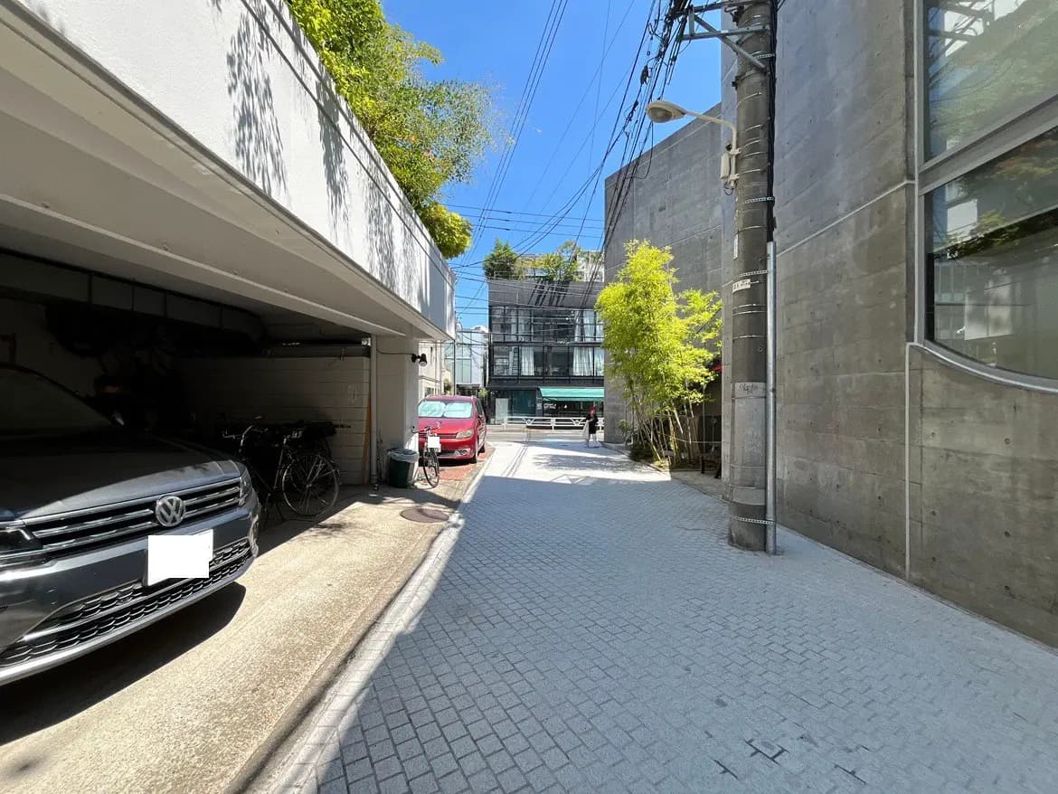 - 駐車場と自転車置き場が見える街並み、コンクリートの建物と青空が広がる風景