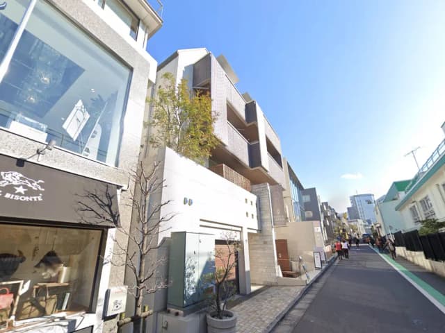- おしゃれなショップが並ぶ街並み、洗練された建築デザインと青空の風景、散策する人々が見える通り