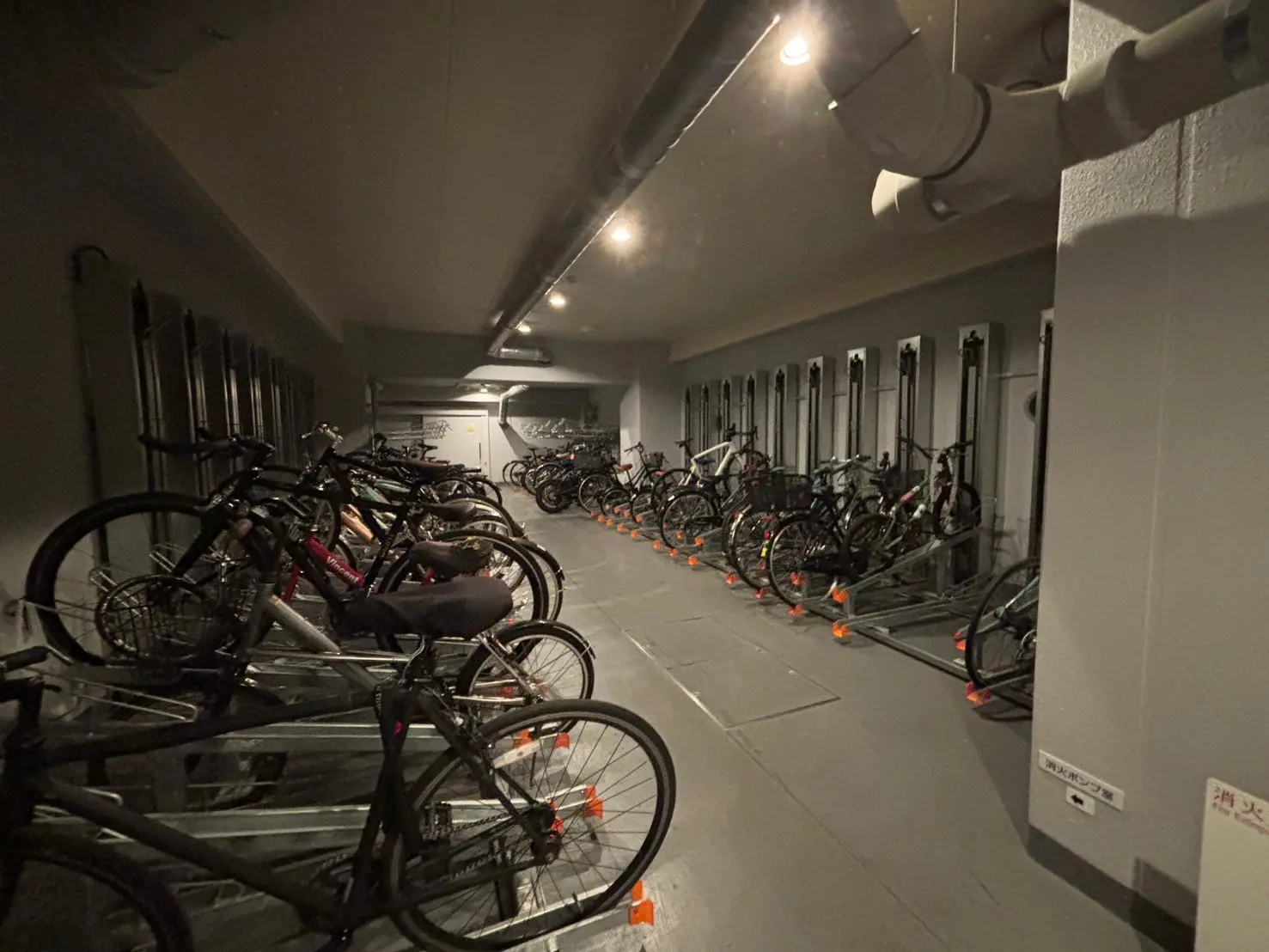- 照明が整備された自転車置き場、多数の自転車がラックに固定されている内部の様子