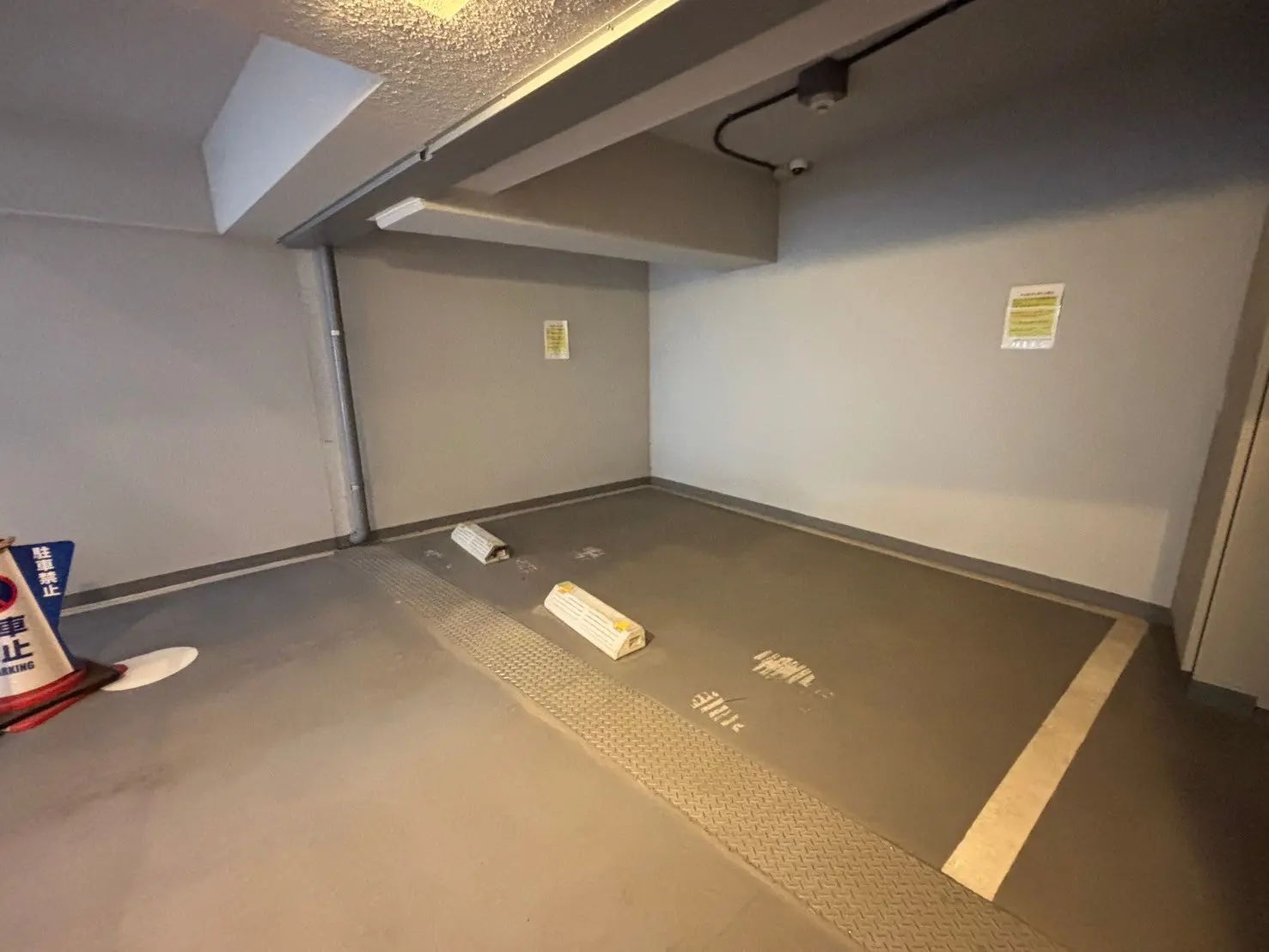 - シンプルで広々とした駐車場の内部、グレーの壁と床、表示看板が設置された空間