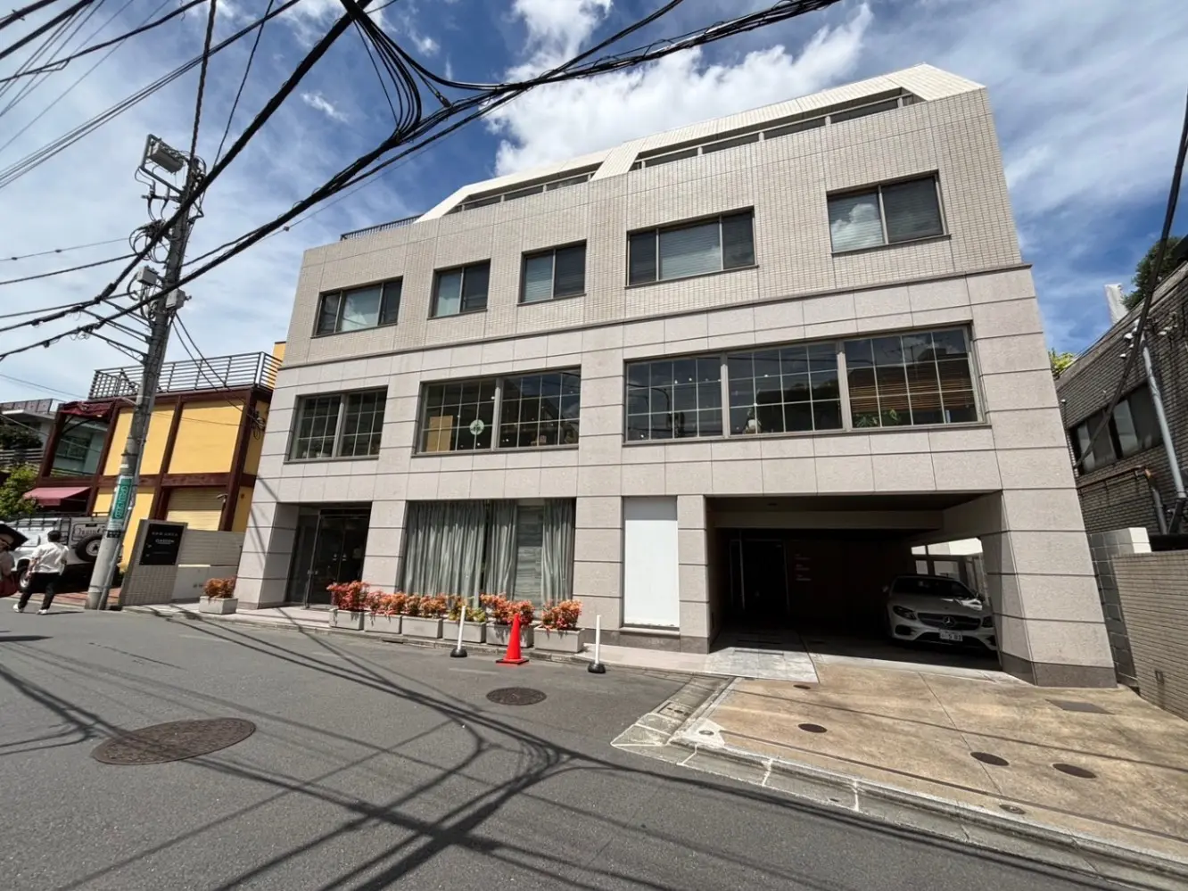 - 近代的なテナントビルの正面、ガラス窓とアウトドアファサード、道路に面したエントランスと花壇がある景観