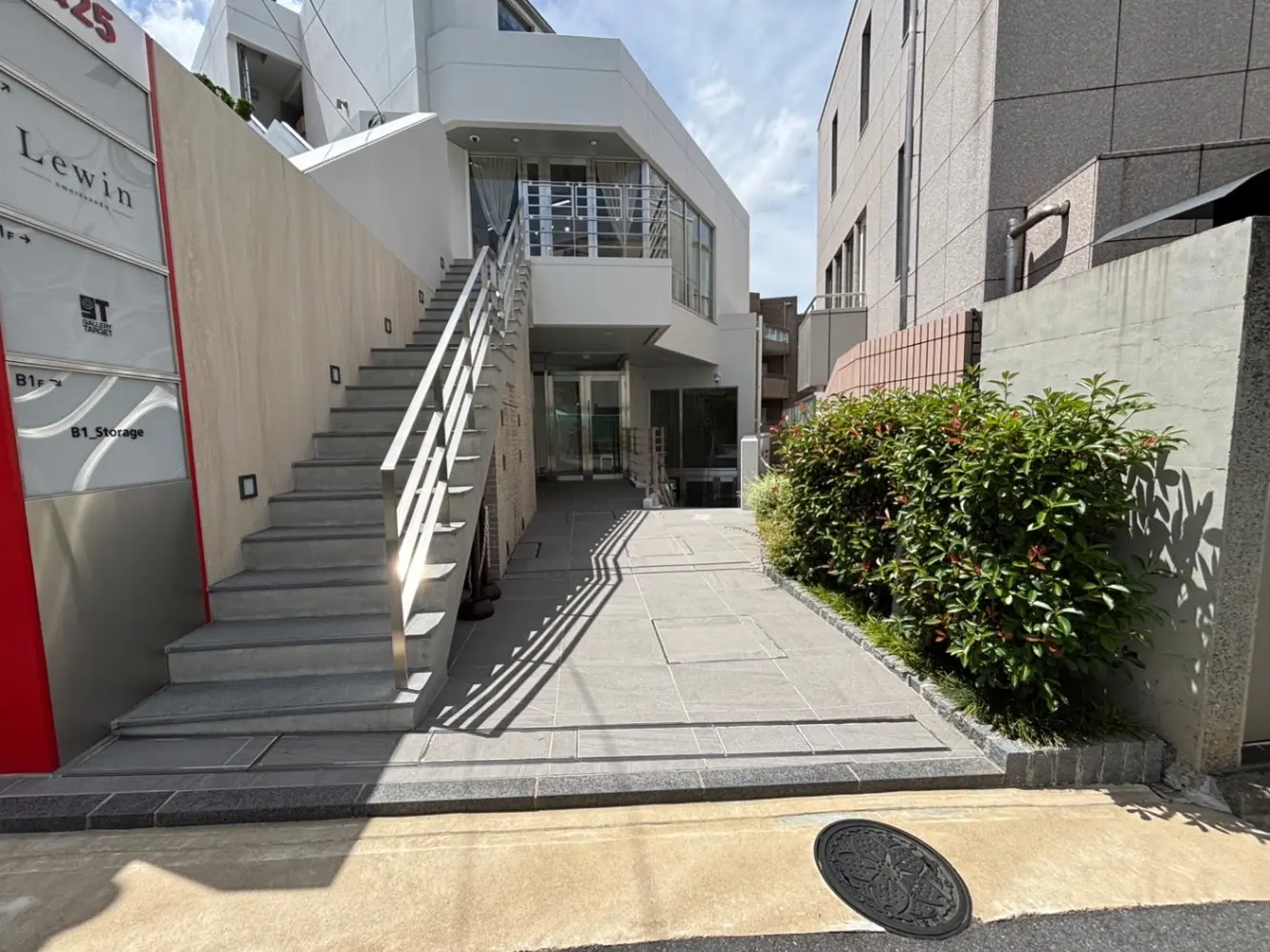 - 現代的な建物のエントランス、階段と緑の植栽、明るい天候のもとで撮影された外観の風景