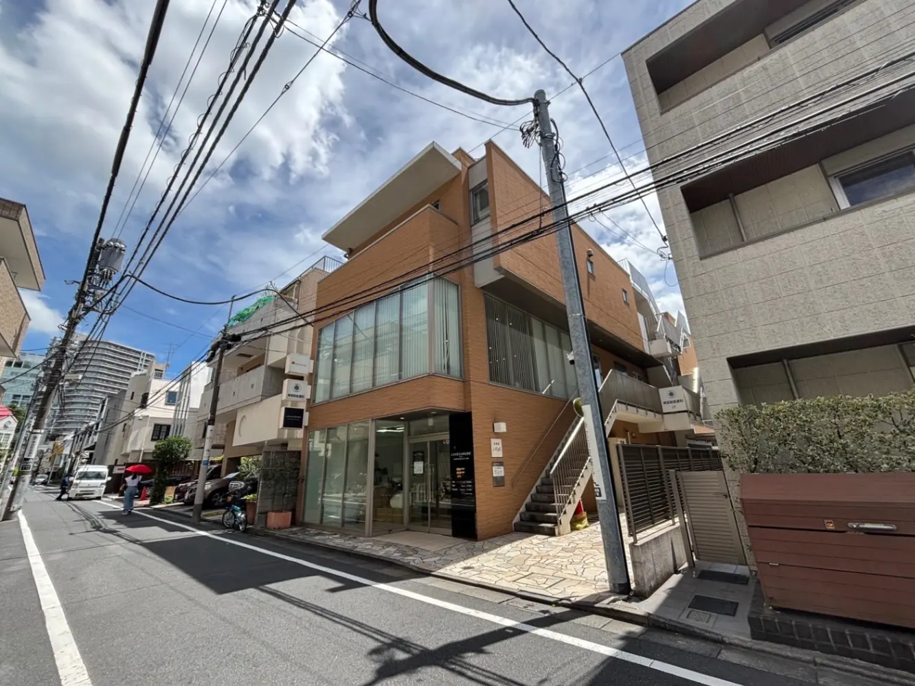 - 近代的なデザインの商業ビル、ガラス張りの外観と周囲の街並み、青空の下に位置する様子