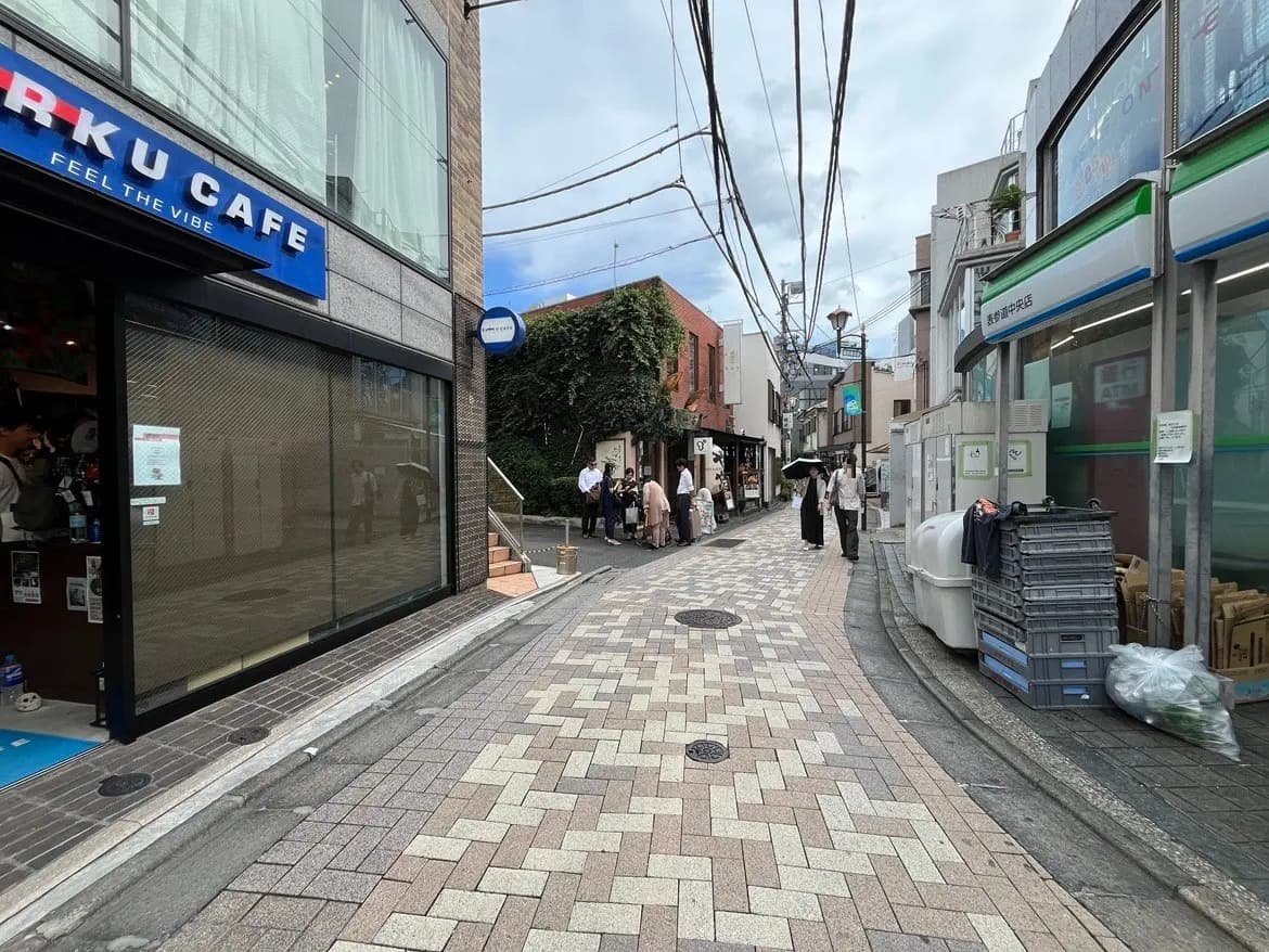 - 狭い街並みの通り、カフェの看板や商店が並ぶ、人気のあるエリアで人々が行き交う様子