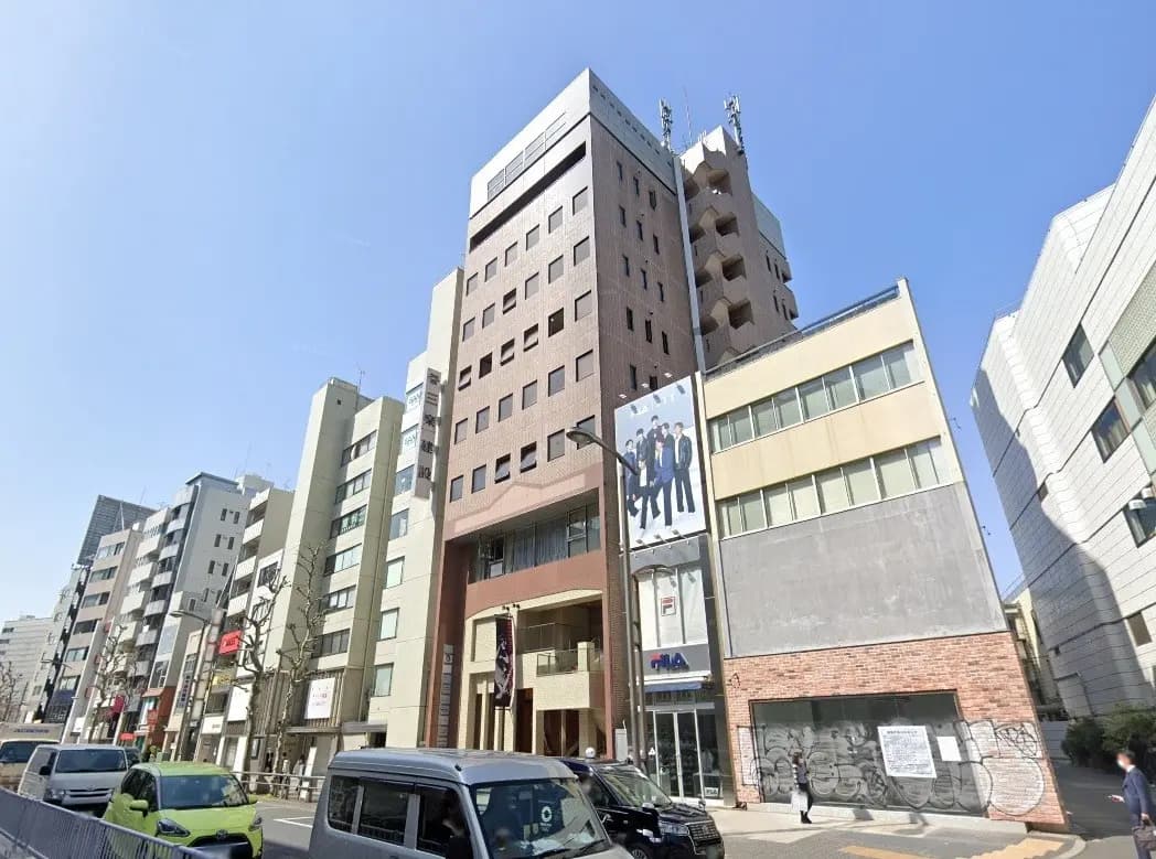 - 都市のビル群、異なるデザインの商業ビルと大通りに停車中の車両、青空の下での街並み