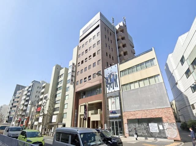 - 都市のビル群、異なるデザインの商業ビルと大通りに停車中の車両、青空の下での街並み