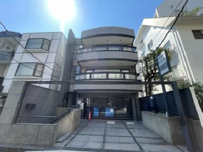- モダンなデザインの建物外観、バルコニー付きの多階建て、明るい空と日差しが映える景観